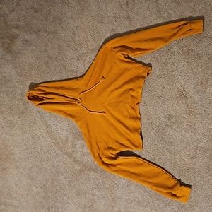 This is a mustered colored cropped hoodie.